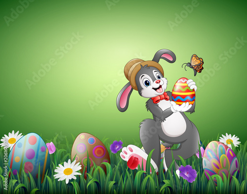 Fototapeta Naklejka Na Ścianę i Meble -  Happy Easter bunny holding Easter eggs in a field