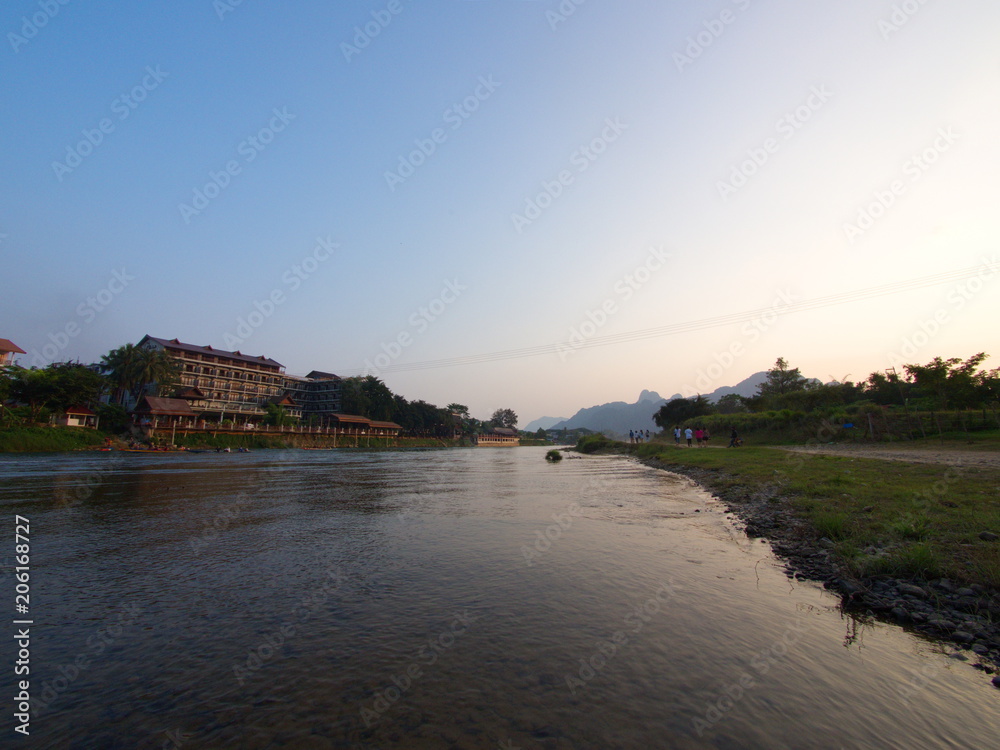 Fototapeta premium Sunset at Riverside with mountain background , Travel in Vang Viang City, Laos. 5th December, 2013.