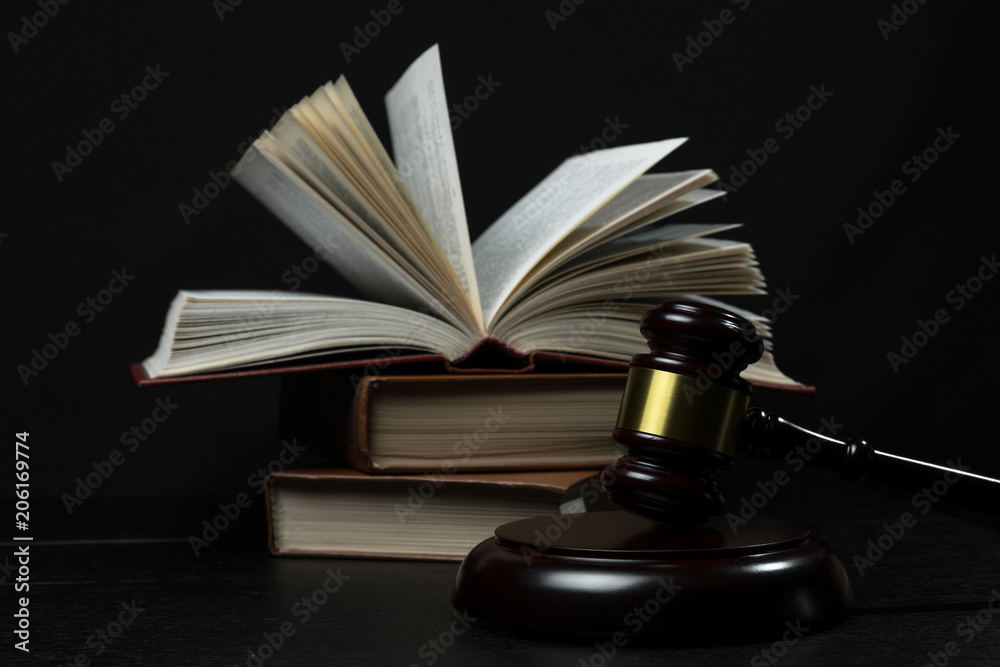 Judge gavel beside pile of books on wooden background Judge gavel beside pile of books on wooden background