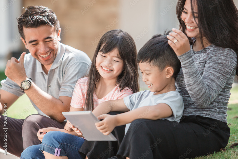 family in front of their house using tablet family in front of their house using tablet