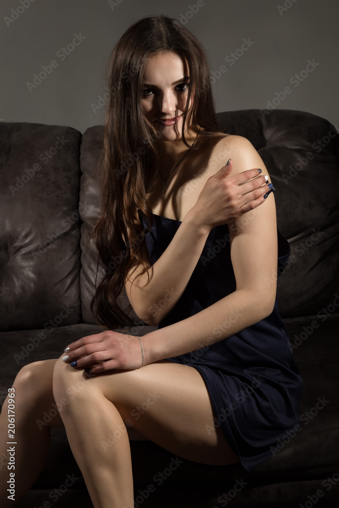 Sensual attractive young woman in a silk pajamas poses on a sofa. Sensual attractive young woman in a silk pajamas poses on a sofa.