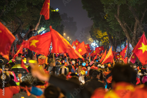 Blurred background of crowd of Vietnamese football fans down the street to celebrate the win after soccer, with a lot of Vietnamese flags raising high © Hanoi Photography