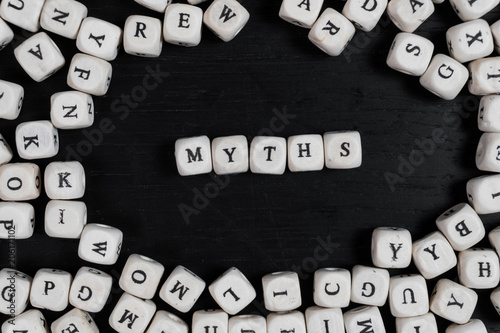 Word MYTHS on wooden cubes on a black wooden table with copy space