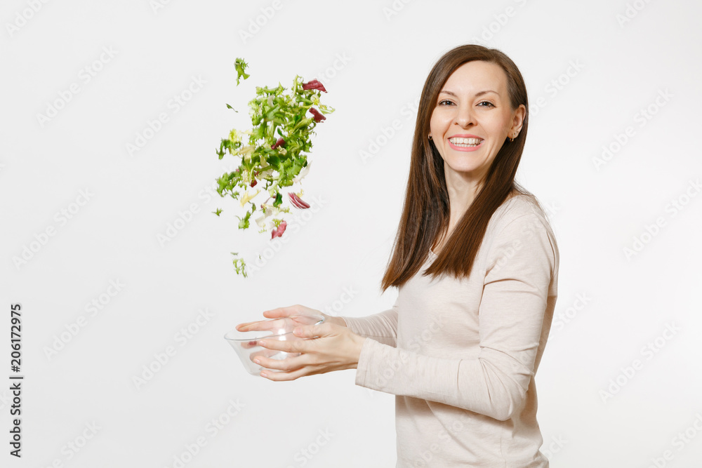 Young happy fun woman standing and throwing up salad from glass bowl isolated on white background. Proper nutrition, vegetarian food, healthy lifestyle, dieting concept. Advertising area to copy space Young happy fun woman standing and throwing up salad from glass bowl isolated on white background. Proper nutrition, vegetarian food, healthy lifestyle, dieting concept. Advertising area to copy space