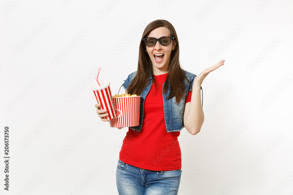 Young shocked laughing woman in 3d imax glasses watching movie film, holding bucket of popcorn and plastic cup of soda or cola, spreading hand isolated on white background. Emotions in cinema concept. Young shocked laughing woman in 3d imax glasses watching movie film, holding bucket of popcorn and plastic cup of soda or cola, spreading hand isolated on white background. Emotions in cinema concept.