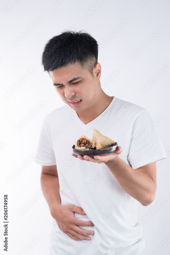 A man has a stomachache after eating delicious zongzi(rice dumpling) on Dragon Boat Festival, Asian traditional food, white background A man has a stomachache after eating delicious zongzi(rice dumpling) on Dragon Boat Festival, Asian traditional food, white background