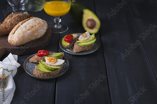 Tasty and juice , sandwich with avocado, tomato and poached egg on wooden chopping board, close up, selective focus. Healthy delicious breakfast or lunch. On a dark background, top view. text