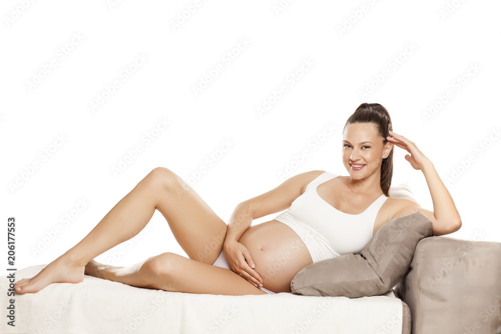 young pregnant pretty woman sitting on a bed on a white background young pregnant pretty woman sitting on a bed on a white background