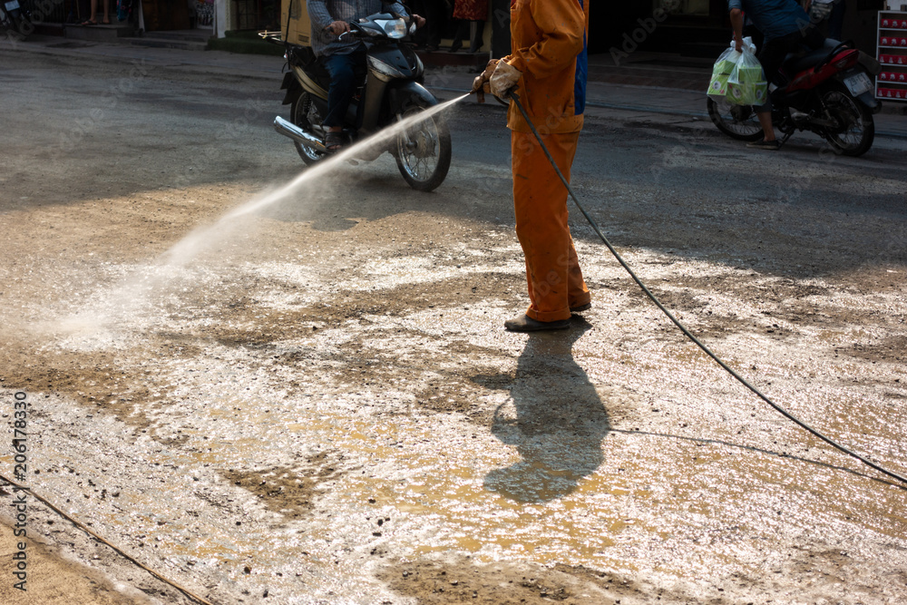 Worker making street wet with water spray at construction area Worker making street wet with water spray at construction area