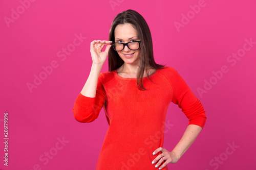 Beautiful brunette woman in glasses on a pink background.
