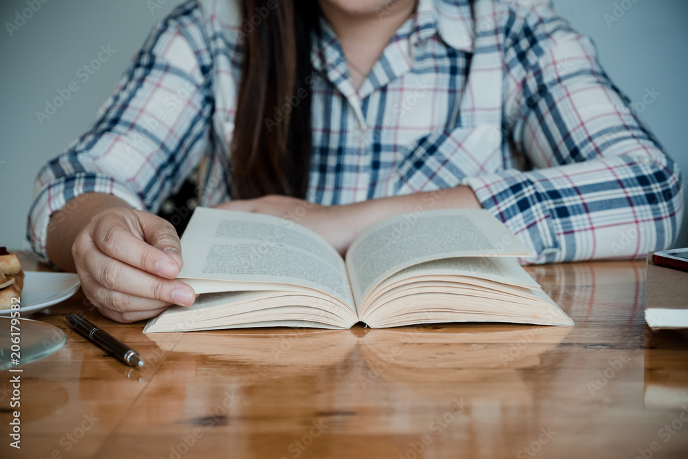 Beautiful girl sitting by wooden table and reading book Beautiful girl sitting by wooden table and reading book