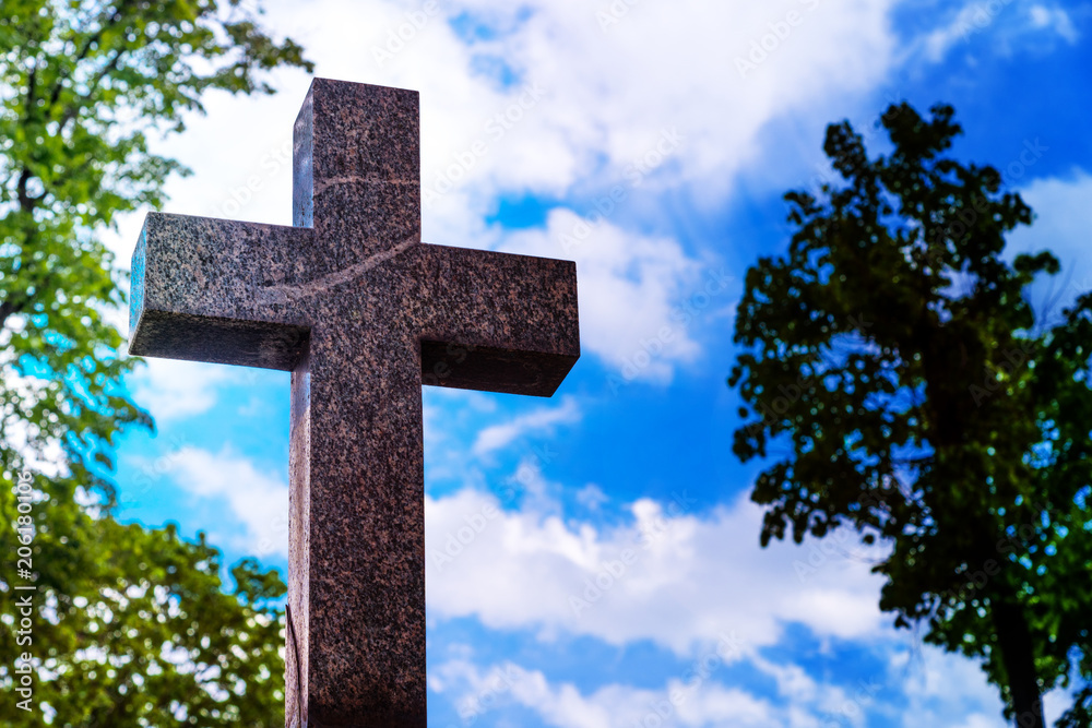Stone cross on the sunset sky background - concept of the Christian faith