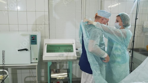 Wallpaper Mural Sterile operating theater. The doctor is getting ready for surgery. The nurse helps him put on a special gown and gloves. Department of Surgery in the hospital. A nurse is preparing a specialist for Torontodigital.ca