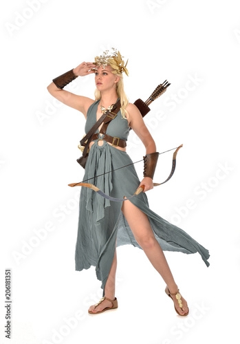 full length portrait of pretty blonde lady wearing fantasy toga gown,  and holding a bow and arrow. standing pose on white background. © faestock