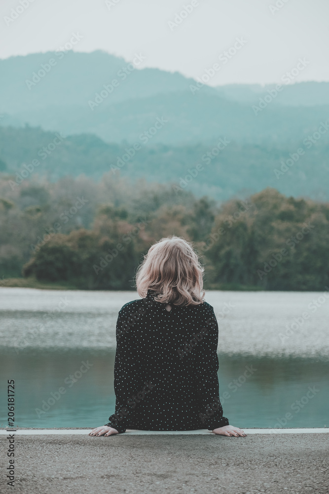 Fototapeta premium Teenager girl sitting alone in the park on moutain background.