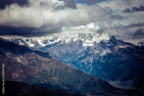 Amazing view to Caucasus Mountains. Adorable high mountain peaks in .thick and dark cumulus clouds. .Village in the mountain valley. Svaneti, Geogria.