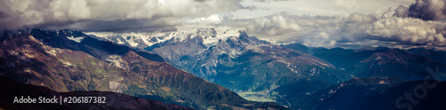 Amazing panoramic view to Caucasus Mountains. Adorable high mountain peaks in thick and dark cumulus clouds. .Village in the mountain valley. Svaneti, Geogria.