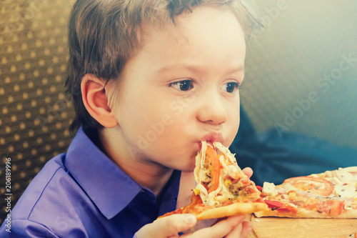 Little boy eating pizza at cafe