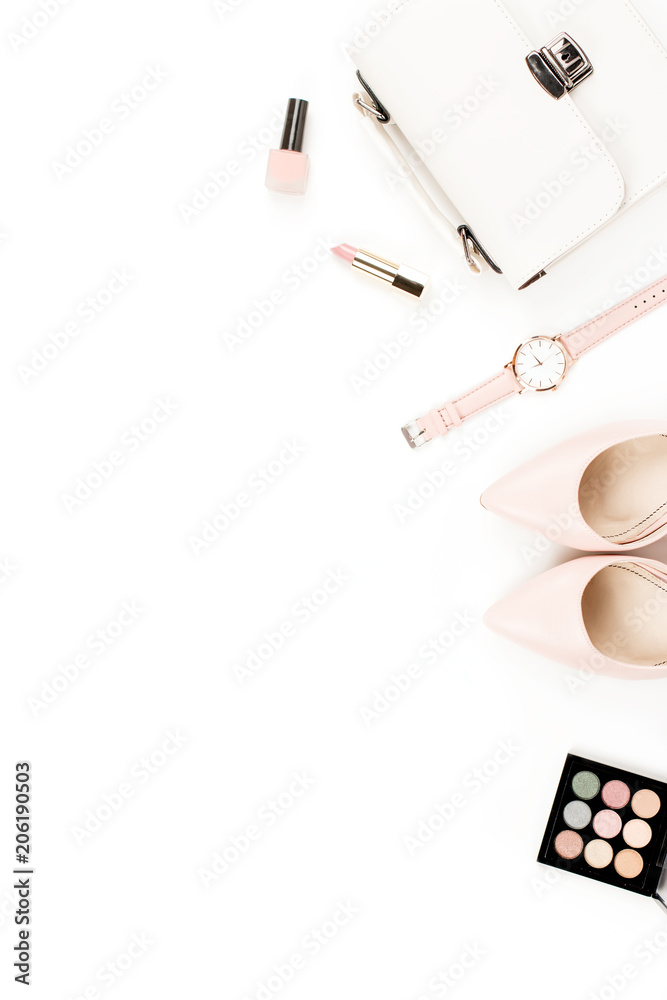Fashion blogger workspace flat lay with pumps, cosmetics, purse, planner book and flowers.