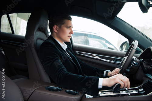 Professionals go only forward! Side view portrait of the handsome confident young entrepreneur carefully driving the automobile. © stacestock