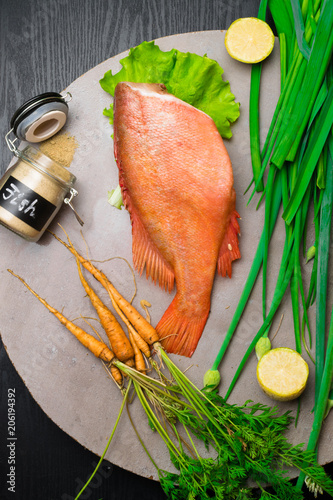 red sea perch on the table with young carrot, spices, lime, green onion photo