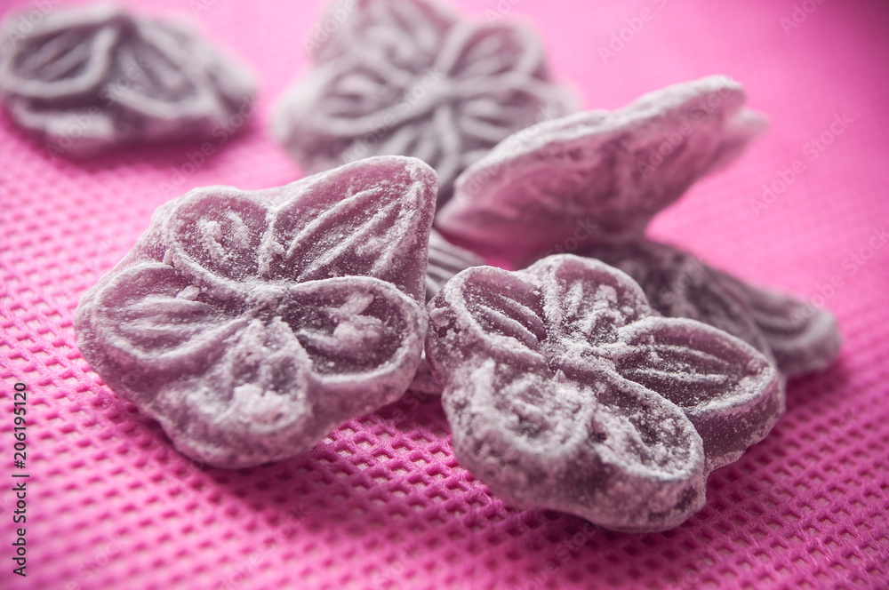 closeup of traditional purple candies in shaped flower on pink background closeup of traditional purple candies in shaped flower on pink background