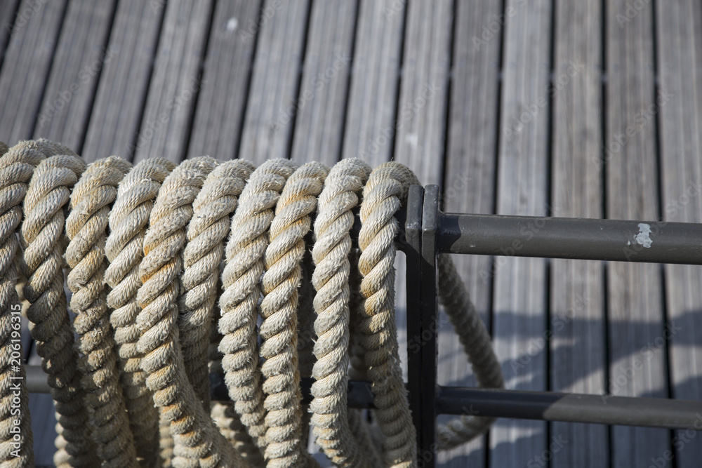 Rigging ropes on board an old wooden sailing ship neatly stored on a metal frame in a close up view with wood decking background Rigging ropes on board an old wooden sailing ship neatly stored on a metal frame in a close up view with wood decking background