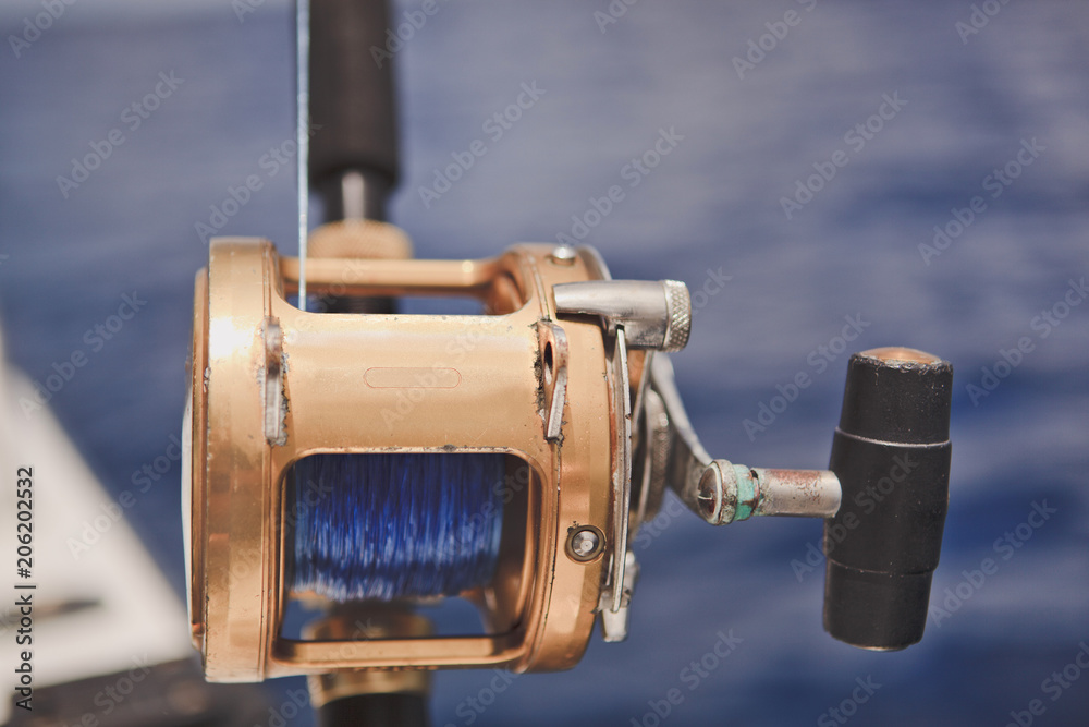 Spinning for sea fishing on the background of the blue ocean. Close up. Spinning for sea fishing on the background of the blue ocean. Close up.