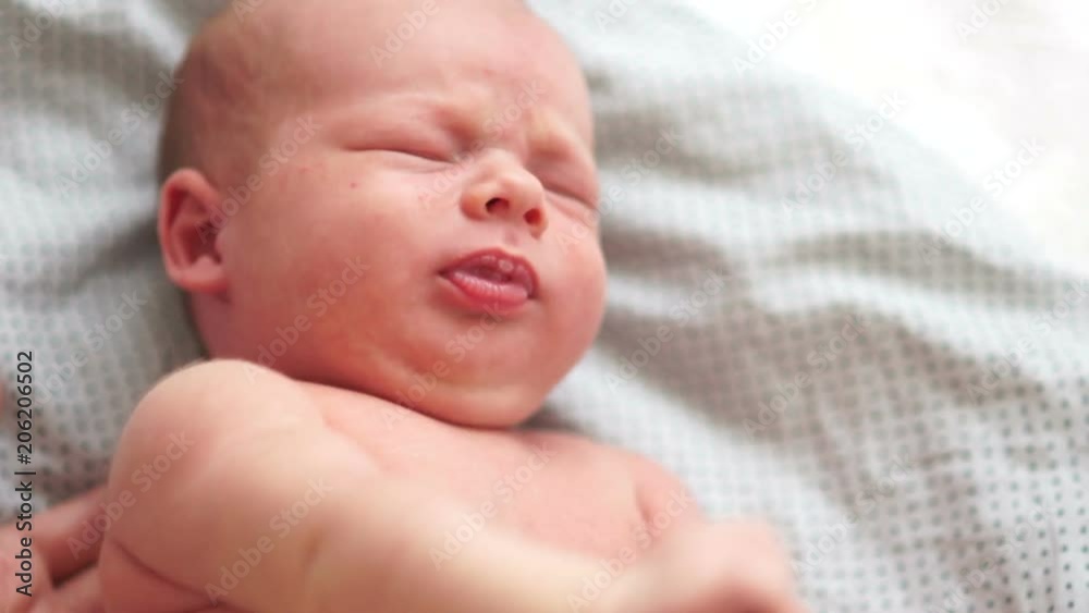 Close-up portrait of a crying newborn baby in bed. A two-week-old baby wakes up from colic. A dream of a newborn. Children's Day. Protection of children