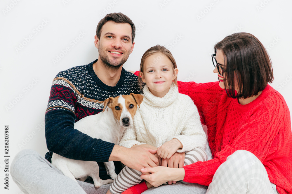Studio shot of happy family of three family members and dog, embrace and smile happily, have good relationships, isolated on white background. Beautiful small kid with her parents and favourite pet Studio shot of happy family of three family members and dog, embrace and smile happily, have good relationships, isolated on white background. Beautiful small kid with her parents and favourite pet