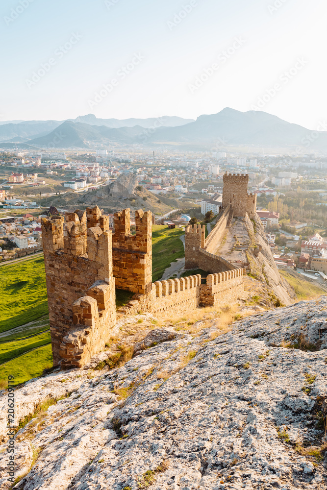 An old defensive fortress with towers in the city of Sudak in the Crimea at dawn.