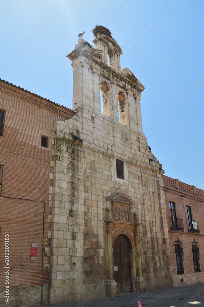 Beautiful Front Facade Of The Church Of Alcala De Henares University With A Nest Of Storks In Its Old Bell Tower. Architecture Travel History. May 5, 2018. Alcala De Henares Madrid Spain.
