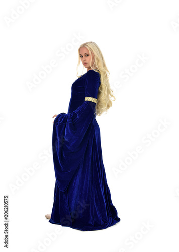 full length portrait of pretty blonde lady wearing  a blue fantasy medieval gown. standing pose on white background.