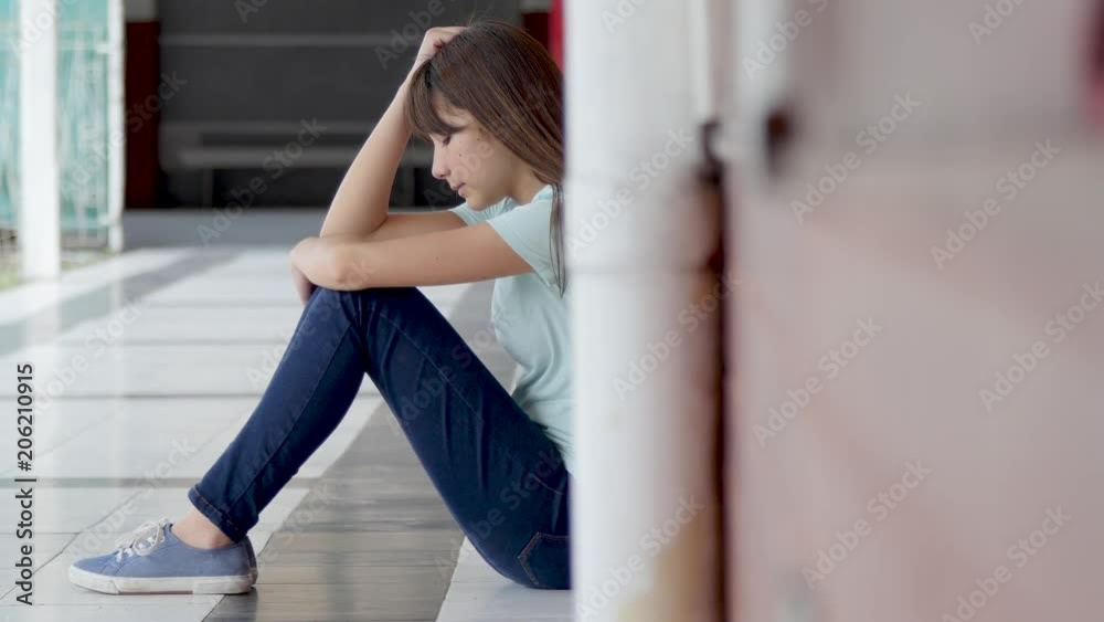 Asian girl Isolated by bullying at school. Seated in school hallway Asian girl Isolated by bullying at school. Seated in school hallway
