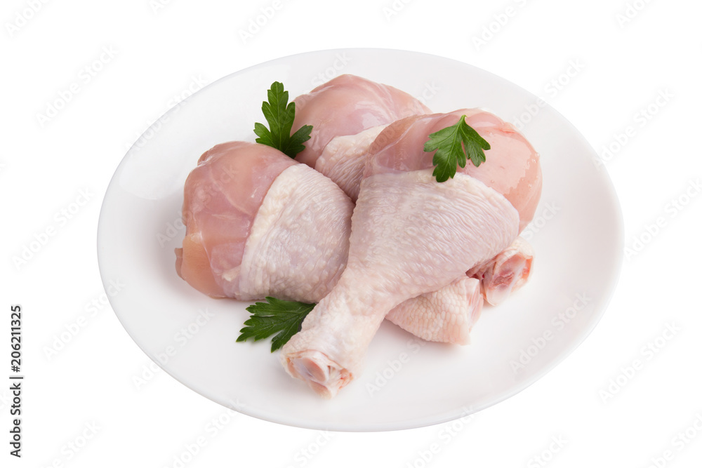 uncooked chicken drumstick on a white plate with greens isolated on white background uncooked chicken drumstick on a white plate with greens isolated on white background