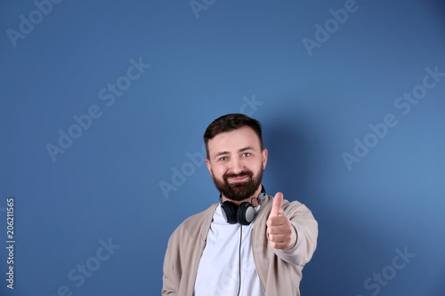 Portrait of handsome bearded man with headphones on color background photo