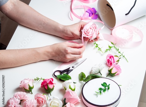 Flower shop: A girl makes a bouquet of roses in a round box. Close-up of hands.