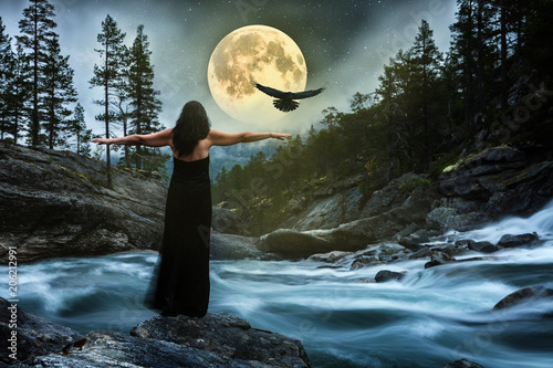 Frau im schwarzen Kleid bei Vollmond am Fluss