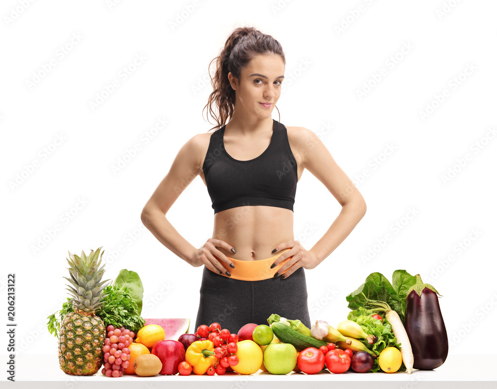 Fitness woman behind a table with fruit and vegetables Fitness woman behind a table with fruit and vegetables