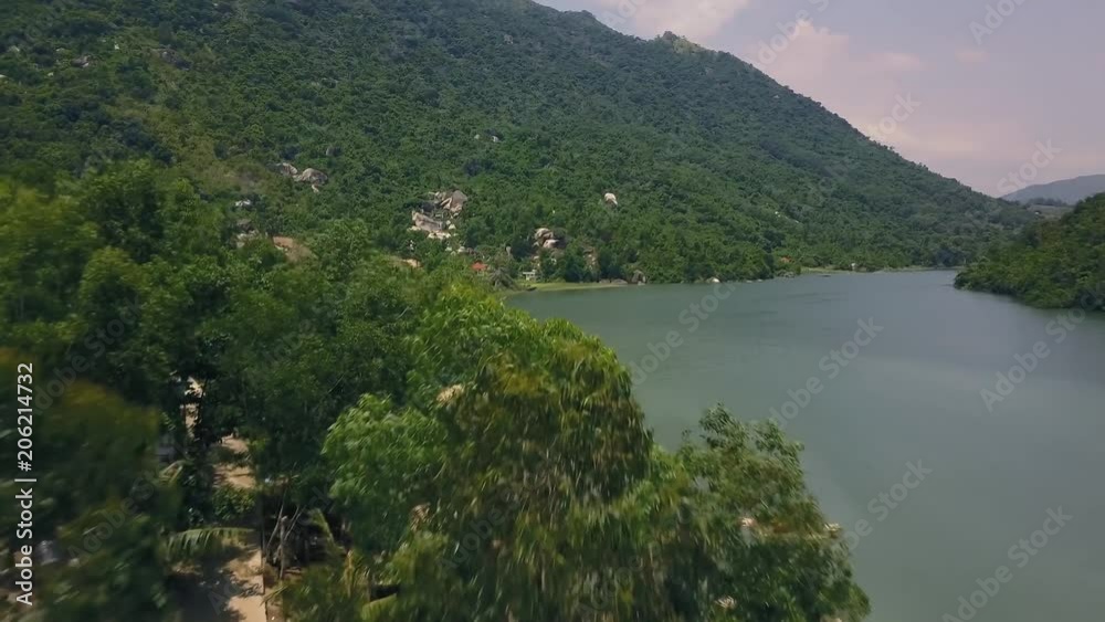 Beautiful mountain river and building on shore aerial view. Road in green mountain drone shoot. Landscape view on green mountain and lake from frying drone.