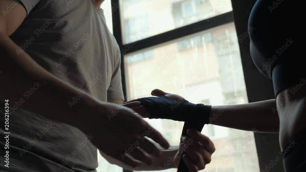 The girl's coach bandages her hands under the boxing gloves. Healthy lifestyle, diet, sports. The girl's coach bandages her hands under the boxing gloves. Healthy lifestyle, diet, sports.