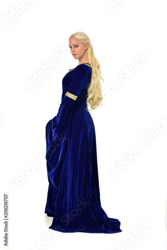 full length portrait of pretty blonde lady wearing a blue fantasy medieval gown. standing pose on white background.