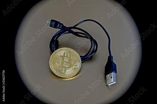 Digital kriptonite bitcoin with a USB cable on a bronze background. photo