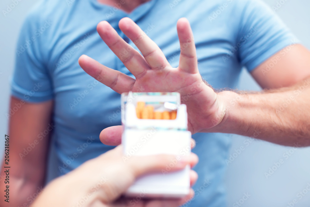 Man refusing a cigarette from a pack of smokes concept for quitting smoking and healthy lifestyle Man refusing a cigarette from a pack of smokes concept for quitting smoking and healthy lifestyle