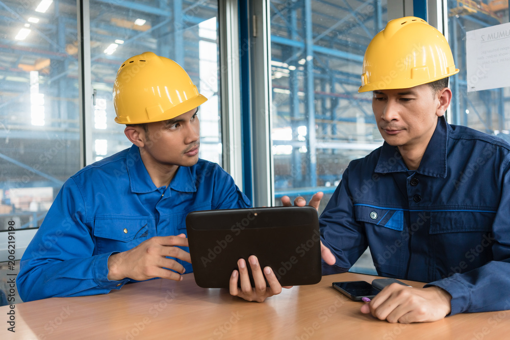 Two Asian skilled workers analyzing information displayed on tablet PC while sitting down indoors Two Asian skilled workers analyzing information displayed on tablet PC while sitting down indoors