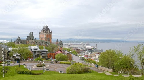 Cityscape or skyline of Quebec City, Canada old town streets green park with cloudy gray stormy sky, Chateau Frontenac, Dufferin Terrace and St Lawrence River, people walking photo