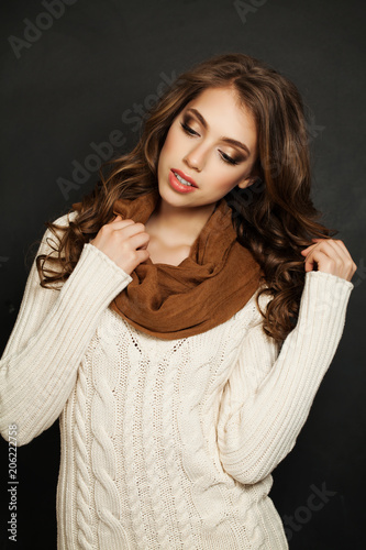 Beautiful Woman with Long Curly Hair and Makeup Wearing White Knitted Sweater and Cotton Scarf on Black Background