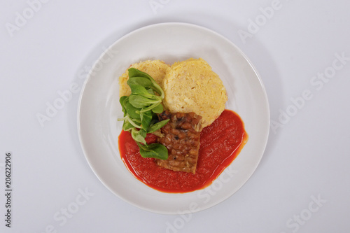 Tempeh with tomato sauce and dumplings on a white