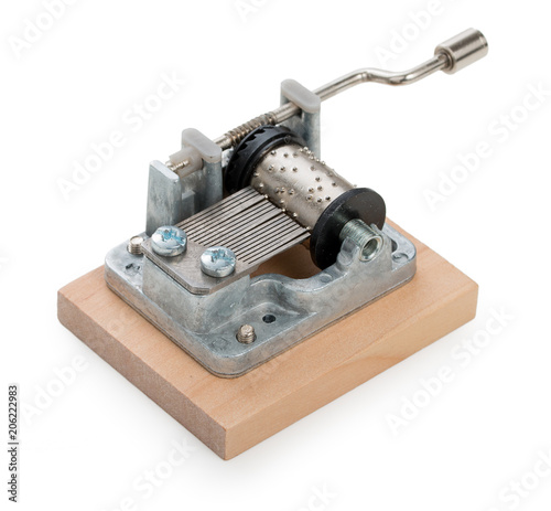 Vintage mechanical music box on a little wooden plank, isolated on white background.