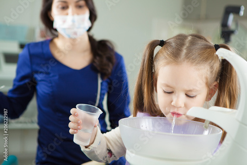 Foto Child rinses out mouth and spit in special sink